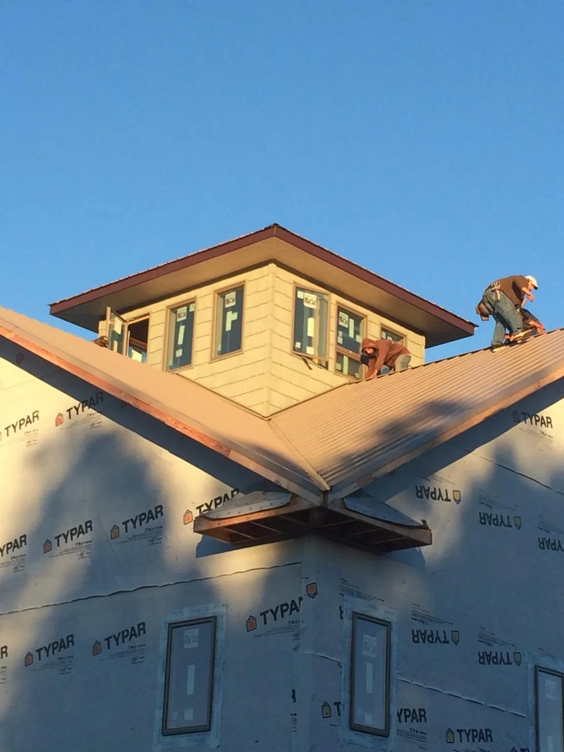 Roofers working around a rooftop cupola on a new metal roof at sunset — Roof Waterproofing in Chatham by Roofing Brothers